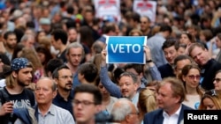 A demonstrator holds up a banner saying "Veto" during a rally against a new law passed by Hungarian parliament that forces the Soros-founded Central European University out of Hungary, in Budapest, April 4, 2017