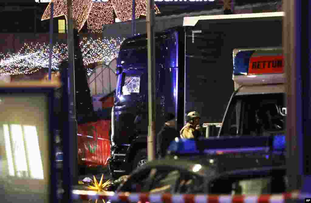 Polisi berdiri di sebelah truk yang hancur setelah menabrak kerumunan orang di pasar Natal di Berlin, Jerman (19/12). (AP/Michael Sohn)