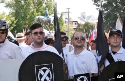 In this Saturday, Aug. 12, 2017 photo, James Alex Fields Jr., second from left, holds a black shield in Charlottesville, Va., where a white supremacist rally took place.