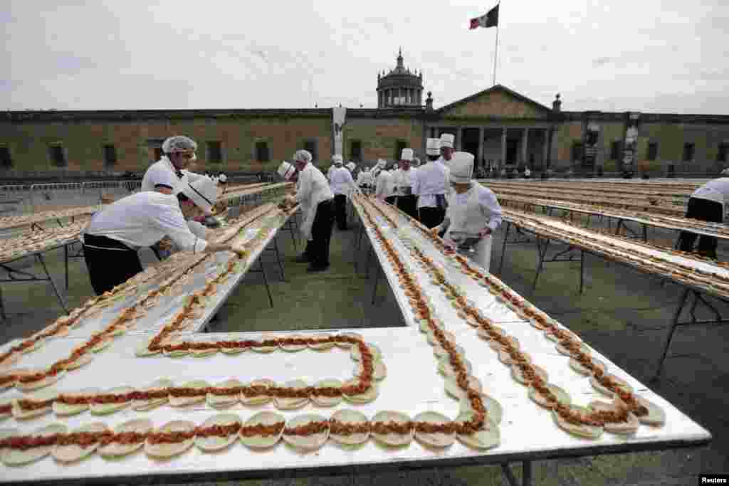 Chefs prepare tacos of cochinita pibil, a popular dish from Yucatan, in an attempt to break the Guinness World Record for the world&#39;s longest taco in Guadalajara, Mexico, Feb. 15, 2015. Guadalajara broke the Guinness record for the longest taco, with a length of 2.5 kilometers, as part of the COME gastronomy festival, local media reported. The chefs used 4 tons of pork, 36,000 tortillas and spices for 325 taco servings.