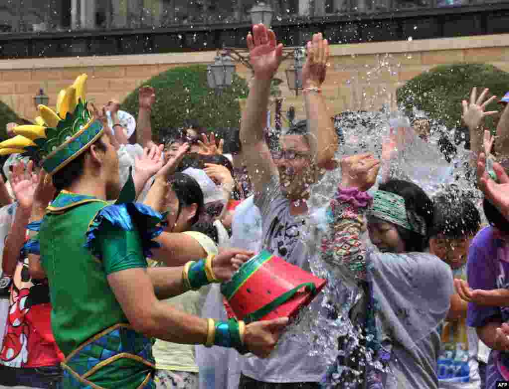 A Tokyo DisneySea cast member (L) sprays a bucketful of water towards guests during a special summer attraction called &quot;Minnie&#39;s Tropical Splash&quot; at Tokyo DisneySea in Urayasu.