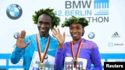Kenya's Eliud Kipchoge and Gladys Cherono (R) celebrate during the victory ceremony after winning the men's and women's 42nd Berlin marathon, in Berlin, Germany, Sept. 27, 2015.