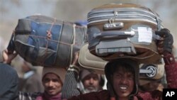 Men from Bangladesh, who used to work in Libya and fled the unrest in the country, carry their belongings as they arrive in a refugee camp at the Tunisia-Libyan border, in Ras Ajdir, Tunisia, March 9, 2011. (AP Imge)