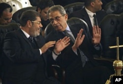 Mohamed Morsi, left, of Egypt's Muslim Brotherhood and Egyptian presidential hopeful Amr Moussa, right, at the Coptic cathedral in Cairo, January 6, 2012