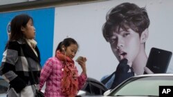 Perempuan China berjalan melewati iklan yang menampilkan idola remaja, Lu Han, yang dikenal sebagai Justin Biebernya China di Beijing, China, 21 Oktober 2017. China berusaha menahan popularitas para selebritis untuk menanamkan nilai-nilai nasionalisme pada anak muda China. 