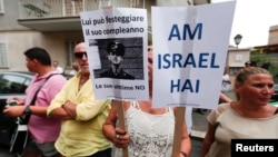 A woman holds signs reading, 'The Jewish People Live' (R) and 'He can celebrate his birthday, his victims no' during a protest against convicted former Nazi SS captain Erich Priebke in Rome, July 29, 2013.