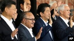 From left, Chinese President Xi Jinping, Papua New Guinea's Prime Minister Peter O'Neill, Japanese Prime Minister Shinzo Abe, and U.S. Vice President Mike Pence wave as they pose for a group photo at APEC Haus in Port Moresby, Papua New Guinea, Nov. 18, 2018.