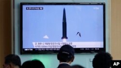 Warga menonton berita televisi yang menunjukkan uji coba rudal Korea Utara di stasiun kereta api Seoul, Korea Selatan, 3 Juni 2015. (AP/Ahn Young-joon)