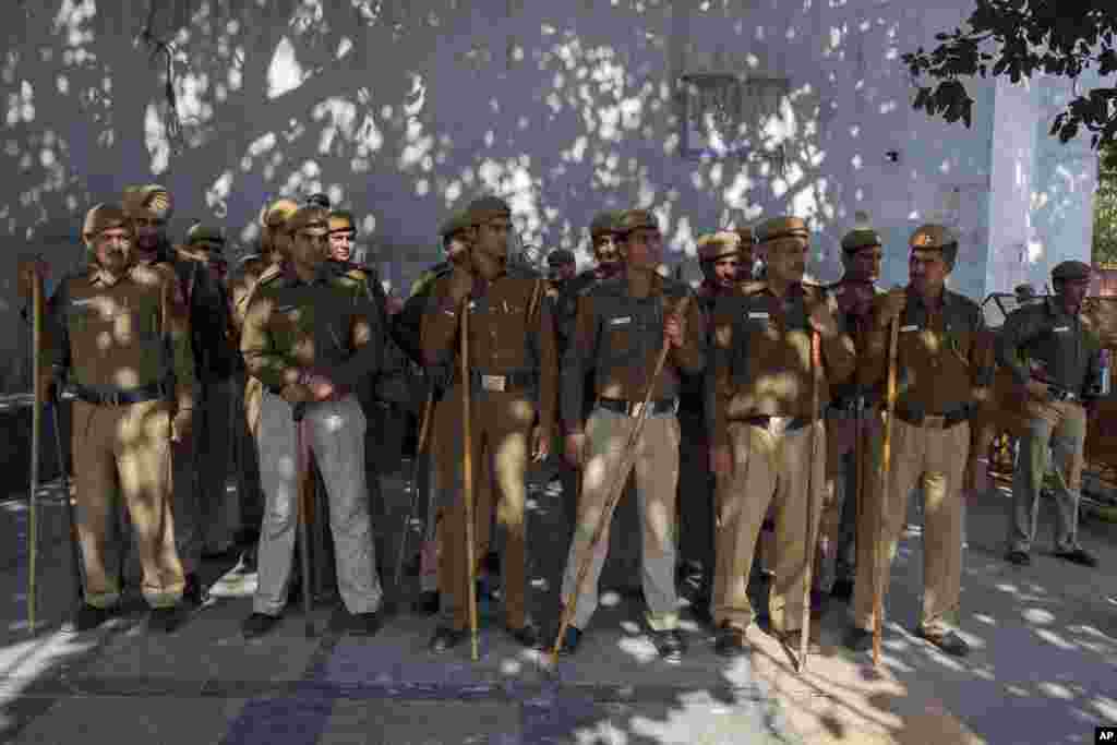 Indian policemen stand guard near the Delhi police headquarters during a protest after a woman was allegedly raped by a taxi driver in New Delhi, India, Monday, Dec. 8, 2014.