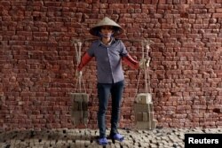 Phung Thi Hai, 54, carries bricks at a factory outside Hanoi, Vietnam, Feb. 27, 2017.