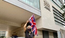 香港社运人士王婆婆9月23日在西九龙裁判法院大楼外，高举英国旗声援民主派初选47人案的被告 (美国之音/汤惠芸)