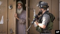 A Palestinian man closes his shop during clashes between Israeli troops and Palestinian protesters, in the West Bank town of al-Ram, north of Jerusalem, Thursday, Oct. 22, 2015.