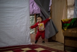 Syrian refugee Rayan, 18 months old, plays inside her parents' tent before they break their fast on the first day of Ramadan, at an informal refugee camp in the town of Bhannine, Lebanon, April 13, 2021.