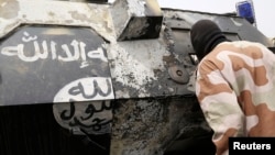 A Chadian soldier peers into a burnt armored vehicle, which the Chadian military say belonged to insurgent group Boko Haram, after the Chadians destroyed it during battle in Gambaru, Feb. 26, 2015.