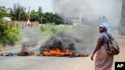 A woman walks past a barricade set on fire by protesters in Maputo, Mozambique, Nov. 7, 2024.