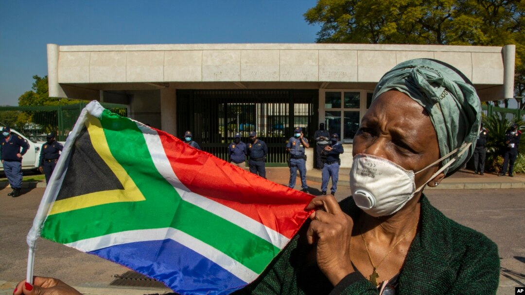 Seorang wanita memegang bendera nasional Afrika Selatan selama protes menentang rasisme di depan Kedutaan Besar AS di Pretoria, Afrika Selatan, Jumat, 5 Juni 2020. (Foto: AP)