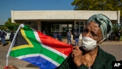 Seorang wanita memegang bendera nasional Afrika Selatan selama protes menentang rasisme di depan Kedutaan Besar AS di Pretoria, Afrika Selatan, Jumat, 5 Juni 2020. (Foto: AP)