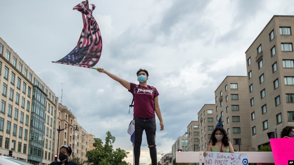 Protester waves U.S. flag with "Black Lives Matter" spray painted on it, Washington, DC, June 19, 2020.
