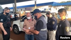 Brazilian citizen Chelbe Willams Moraes is handed a document as he is expulsed from Paraguay, in an unknown location, June 7, 2021. (Courtesy of Direccion General De Migraciones Paraguay/Handout via REUTERS)