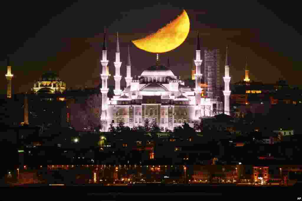 Bulan sabit tampak menjelang terbenam di belakang kubah Masjid Sultanahmet yang dikenal sebagai &quot;Masjid Biru&quot; selama bulan suci Islam Ramadan di Istanbul, Turki. (AP)&nbsp;