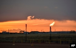 FILE - Flares burn natural gas from oil production in the Fort Berthold Indian Reservation east of New Town, North Dakota, on May 18, 2021.