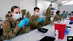 FILE - U.S. Army health specialists fill syringes with the Pfizer COVID-19 vaccine, in Miami, Florida, March 9, 2021.