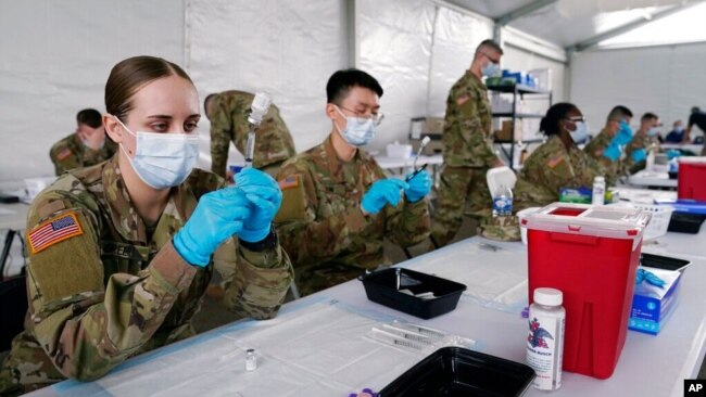 FILE - US Army health specialists fill syringes with the Pfizer COVID-19 vaccine in Miami, Florida, March 9, 2021.