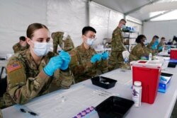 FILE - Army health specialists fill syringes with the Pfizer COVID-19 vaccine in Miami, Florida, March 9, 2021.