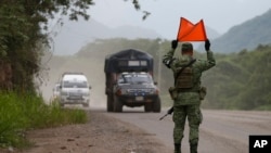 A soldier of Mexico's National Guard signals to stop vehicles at a temporary checkpoint to look for migrants, just north of Ciudad Cuauhtemoc, Chiapas State, Mexico, June 15, 2019. 