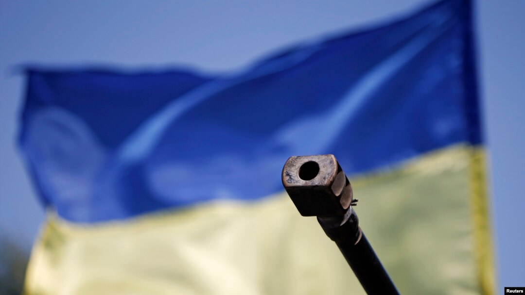 Moncong tank militer Ukraina di depan bendera negara itu terlihat di pos pemeriksaan di Mariupol, Ukraina. (Reuters/Marko Djurica)