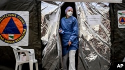 A paramedic wearing a mask gets out of a tent set up by the Italian Civil Protection outside the emergency ward of the Piacenza hospital, northern Italy, Feb. 27, 2020.