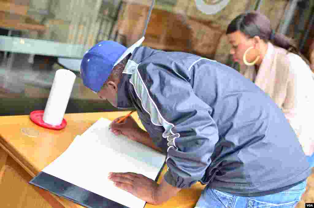 Mourners sign a condolences book outside of the Union Buildings in Pretoria, Dec 6, 2013. (Peter Cox for VOA) 