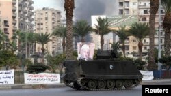 Smoke rises as a Lebanese Army armed vehicle drives through a street in Tripoli, northern Lebanon, Dec.1, 2013.