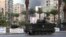 Smoke rises as a Lebanese Army armed vehicle drives through a street in Tripoli, northern Lebanon, Dec.1, 2013.