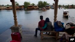 An Indian couple waits for transport as they prepare to leave Srinagar, Indian controlled Kashmir, Saturday, Aug. 3, 2019. 