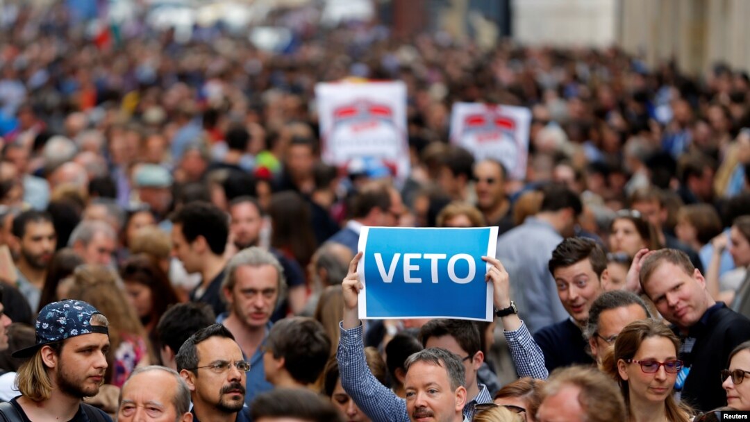 Seorang pengunjuk rasa mengangkat poster yang berbunyi “Veto” selama rapat akbar, menentang undang-undang baru yang disetujui oleh parlemen Hungaria yang dapat memaksa Central European University yang didirikan oleh Soros keluar dari Hungraria, yang diselenggarakan di Budapest, tanggal 4 April 2017 (foto: REUTERS/Laszlo Balogh)