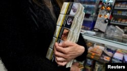 FILE - A woman holds a pack of cigarettes in a tobacco shop at the Vallecas neighborhood, in Madrid,Spain March 13, 2020.