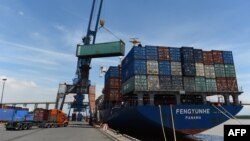 FILE - Containers are transferred from a truck to a cargo ship at the international cargo terminal of a port in Hai Phong, Vietnam, Aug. 12, 2019.