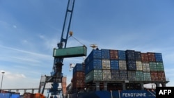 FILE - Containers are transferred from a truck to a cargo ship at the international cargo terminal of a port in Hai Phong, Vietnam, Aug. 12, 2019.