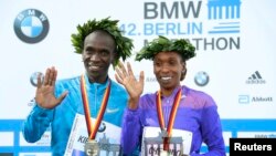 Kenya's Eliud Kipchoge and Gladys Cherono (R) celebrate during the victory ceremony after winning the men's and women's 42nd Berlin marathon, in Berlin, Germany, Sept. 27, 2015.