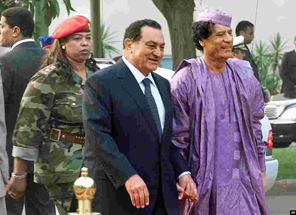 Egyptian President Hosni Mubarak, center, welcoming Libyan leader Moammar Gadhafi, right, who is guarded by a female bodyguard, left, upon his arrival at the Presidential Palace in Cairo, 21 July 2002.