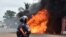 Un officier de police ivoirien se tient près d'un bus en feu à Abidjan, le 10 septembre 2015.