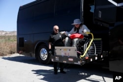 Jennifer Piatek, a planetary geologist at Central Connecticut State University, is helped off the bus during a field trip to the San Andreas Fault, Sept. 26, 2024, in San Bernadino, Calif. (AP Photo/Ryan Sun)