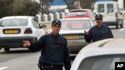 Des policiers contrôlent des véhicules à une barrière, à Alger. 18 mars 2005.