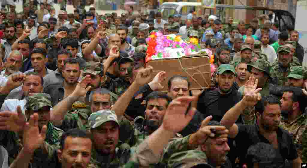 Mourners chant slogans against the Islamic State group as they carry the flag-draped coffins of three members of the Peace Brigades, a Shi'ite militia group loyal to Shi'ite cleric Muqtada al-Sadr during their funeral processions in Najaf, May 27, 2015. 