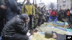 Activistas junto a los cuerpos de manifestantes muertos tras choques con la policía en la Plaza de la Independencia, en Kiev.