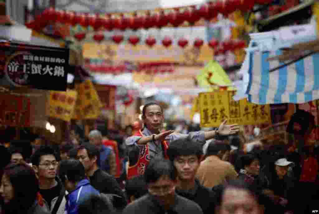An employee tries to lure customers to his stall as crowds pack the traditional market selling candies and fruits for the upcoming Chinese Lunar New Year in Taipei, Taiwan, Friday, Jan. 20, 2012. The first day of the Year of the Dragon falls on Monday, Ja