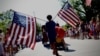 A boy carries American flags through Barnstable Village, Massachusetts, on Cape Cod during the annual Fourth of July Parade celebrating the country's Independence Day on July 4, 2024.