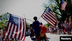 Un niño porta banderas estadounidenses a través de Barnstable Village en Cape Cod, durante el desfile anual del 4 de julio que celebra el Día de la Independencia del país, en Barnstable, Massachusetts, EEUU, 4 de julio de 2024.