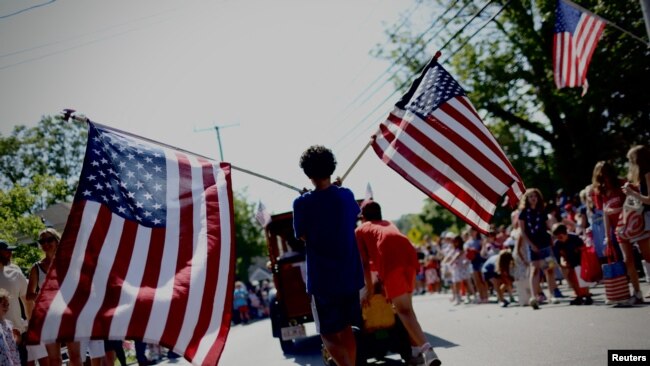 Un niño porta banderas estadounidenses a través de Barnstable Village en Cape Cod, durante el desfile anual del 4 de julio que celebra el Día de la Independencia del país, en Barnstable, Massachusetts, EEUU, 4 de julio de 2024.